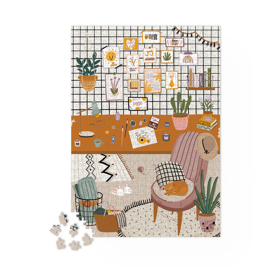 Puzzle L’Atelier en cours d’assemblage sur une table. Pièces du cadre déjà posées.