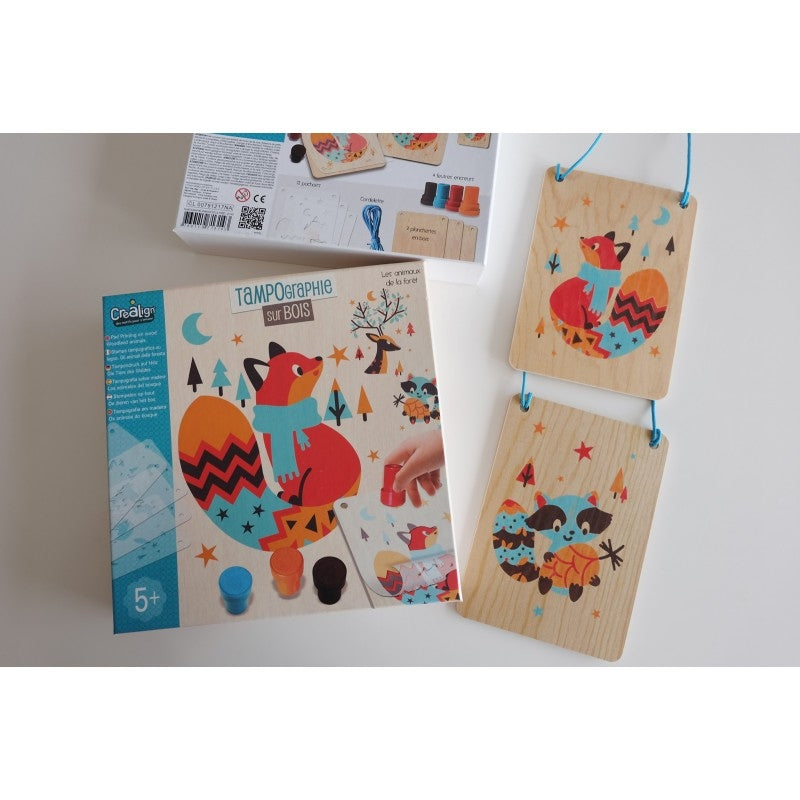 Enfant utilisant les tampons de couleur sur pochoirs pour créer un animal en bois